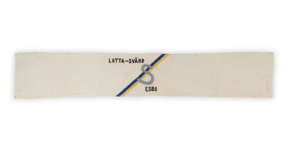 Lottamerkit kuvailtuna: Standardimukainen käsivarsinauha, jossa poikkiviiva 45 asteen kulmassa ja S kirjain