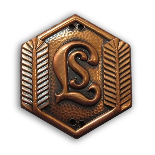 Lottamerkit kuvailtuna: pikkulottien pronssinen hiihto- ja kävelymerkki, jossa havukoristelu reunoilla ja keskellä kirjaimet LS