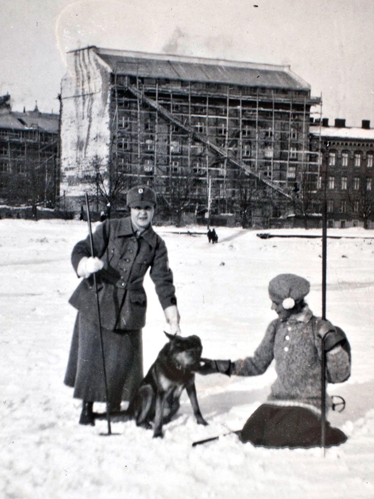 Kuvassa sarkapukuinen lotta koiran kanssa todennäköisesti 1920-luvun alussa.
