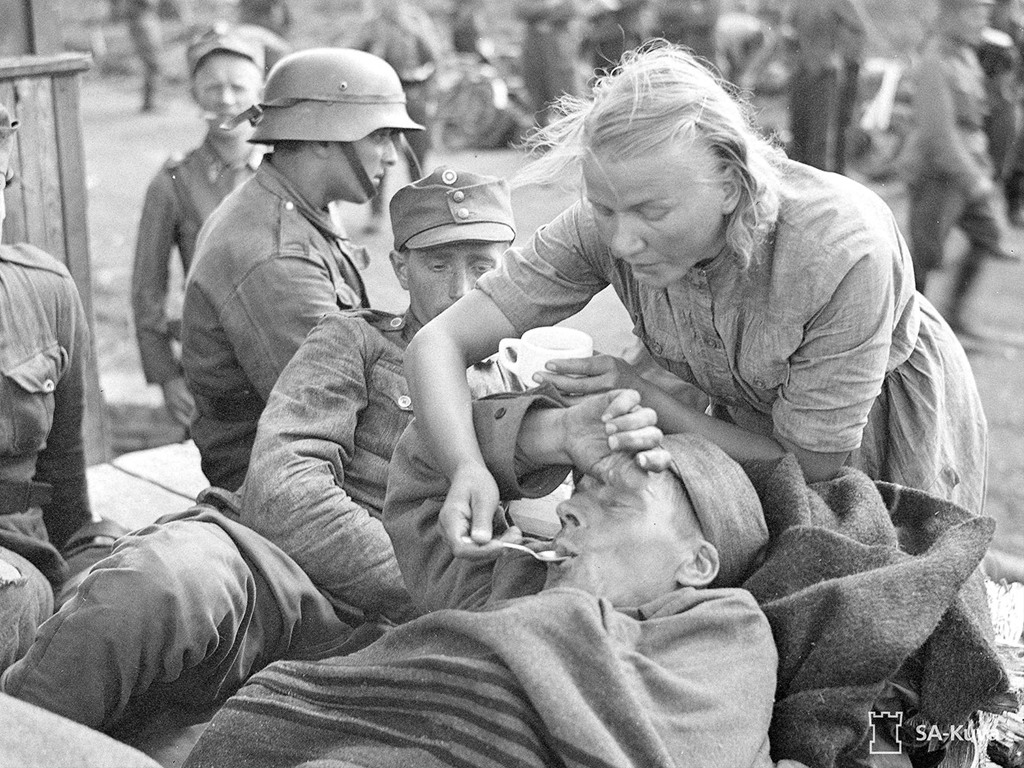 ”Ikonisten” paljon käytettyjen kuvien joukkoon voidaan laskea mm. kyseinen SA-kuva, jossa äidillinen lotta hoivaa sotilasta.