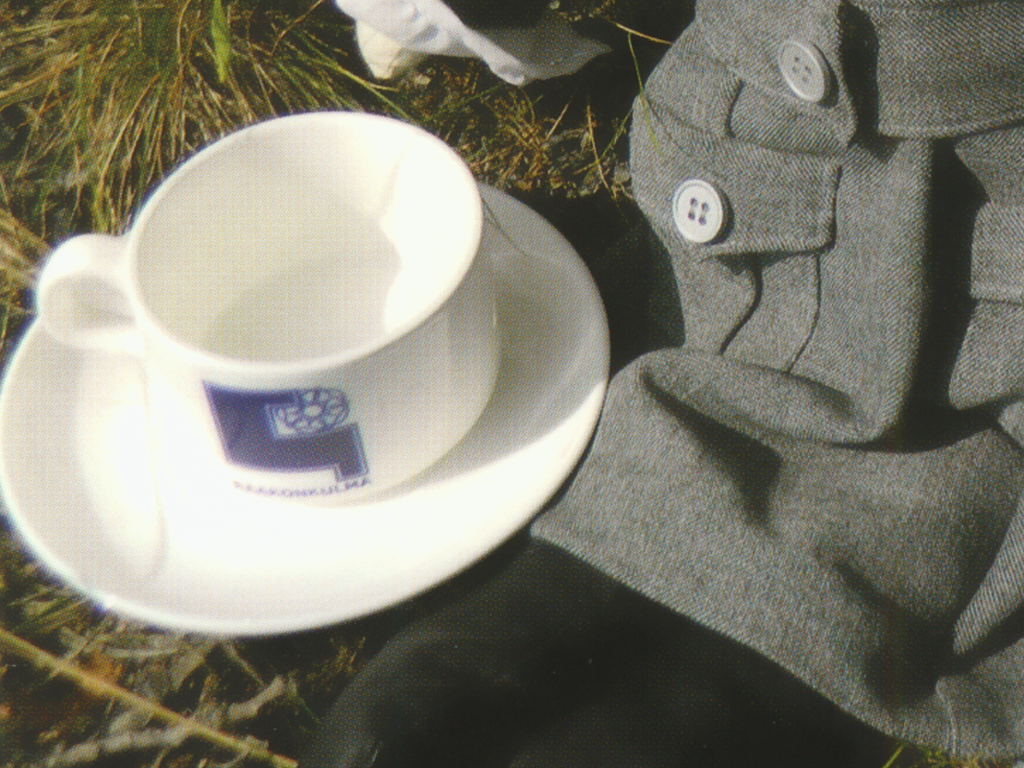 Kaakonkulman lottaperinneyhdistyksen postikortissa lottanostalgiaa edustaa lottakuppityylinen kahvikuppi, jossa on lottaperinneyhdistyksen logo ja nimi Kaakonkulma. Kuvaaja Terttu Ravi.