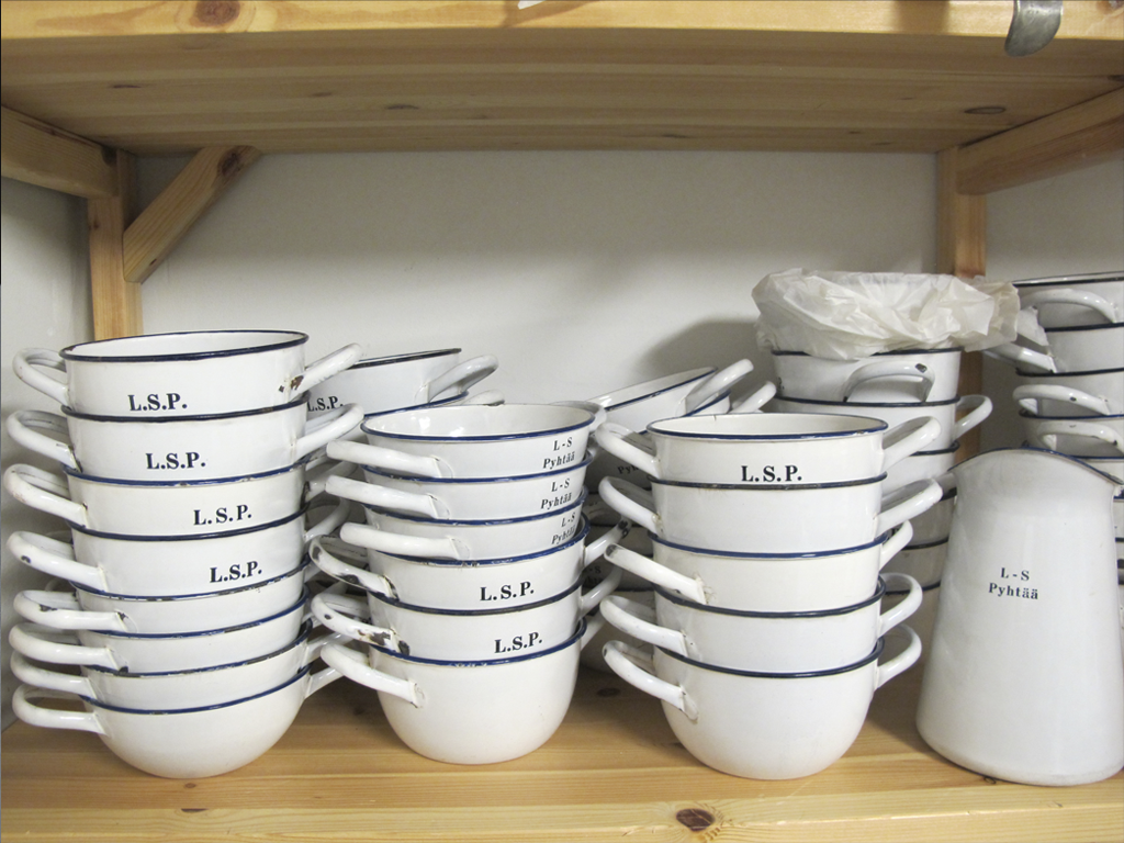 Lotta Svärd Pyhtään astiastoon kuuluvia emaliastioita. Emaliastioita on säilynyt vähemmän kuin posliiniastioita, koska emalimukit ja -kipot ovat olleet kovassa käytössä.