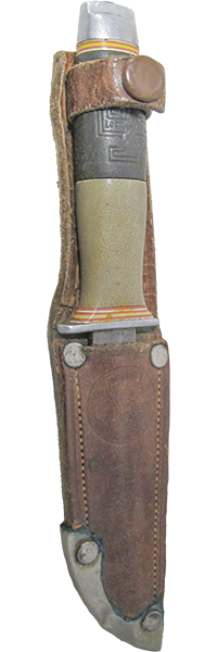 Lottapuukko tupessa. Tupen varressa on pitkät aukot vyön pujottamiseksi niiden läpi. Taskun päälle painettu mahdollisesti partiolilja.