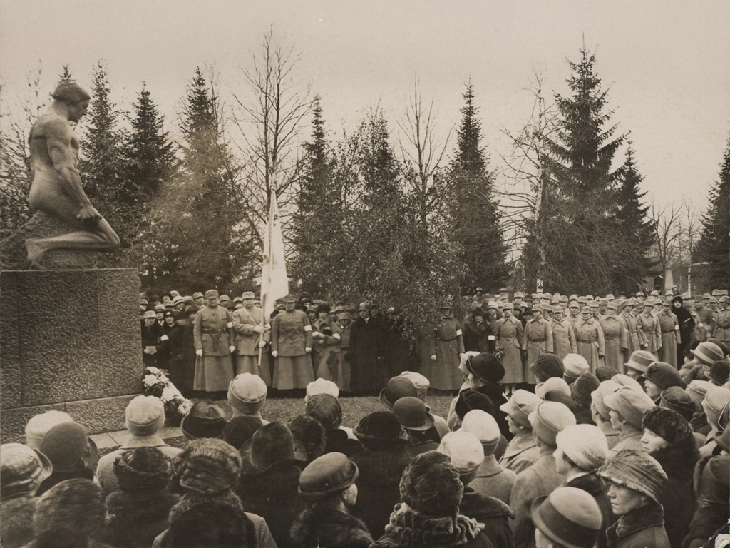 Lottia Tampereella sankarihaudoilla vuonna 1926. Kuvan taakse on kirjoitettu kuvausaika ja paikka, mutta kuvan voisi ajoittaa 1920-luvulle myös lottien sarkapukujen ja naisyleisön hattumuodin perusteella.
